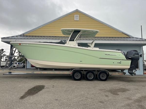 World Cat 280 CC-X 2023 World Cat 280 CC-X boat on trailer, parked outside a yellow building.