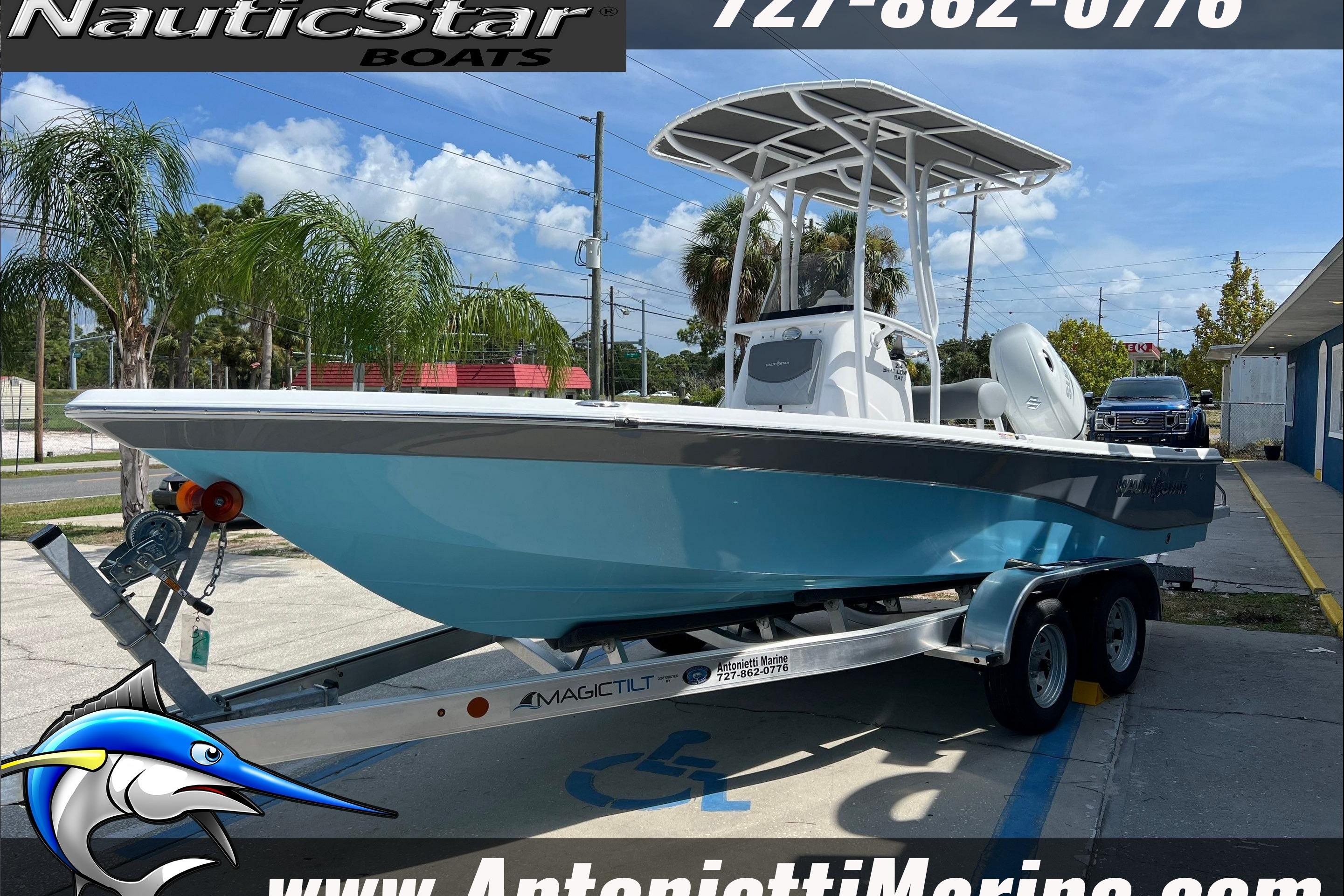 NauticStar 214 Shallow Bay 2025 NauticStar 214 Shallow Bay boat on trailer, displayed outdoors with palm trees.