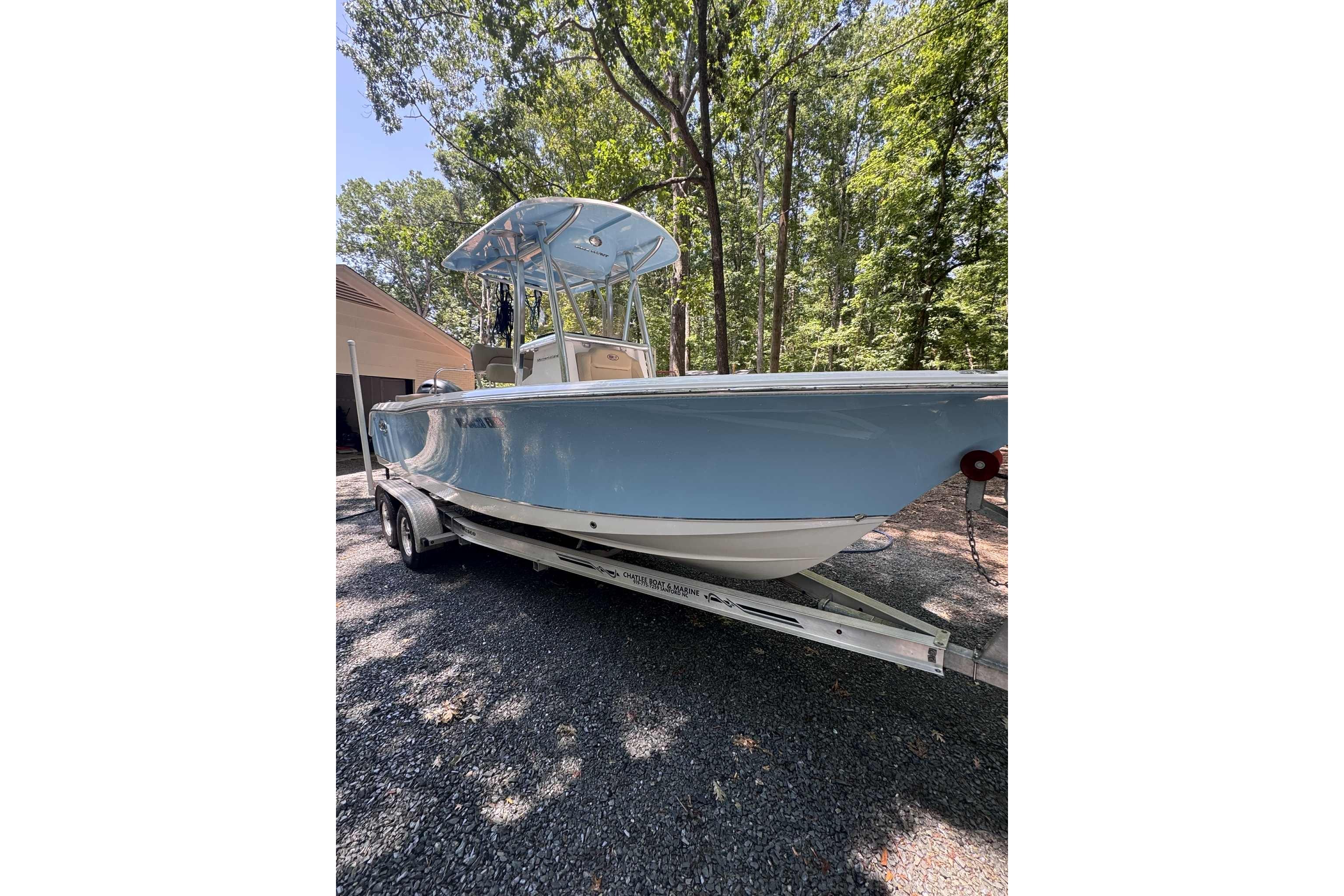 Sea Hunt Ultra 234 2018 Sea Hunt Ultra 234 boat on trailer, parked outdoors under trees.