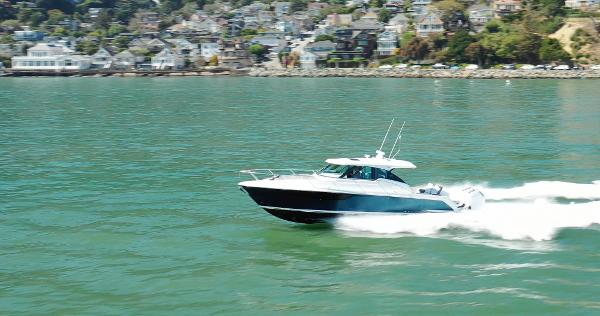 Tiara Yachts 43 LE 2022 Tiara Yachts 43 LE cruising on a scenic waterway with houses in the background.