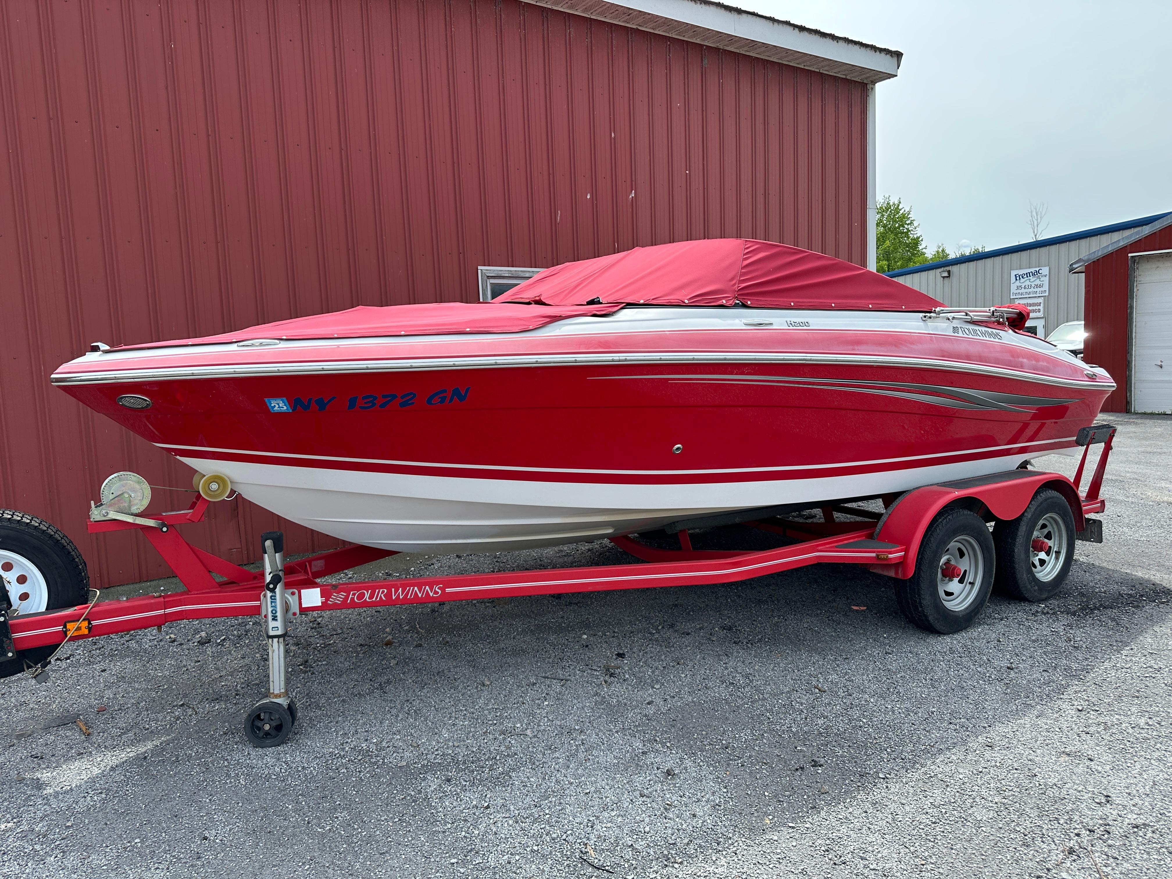 Four Winns H200 Red 2009 Four Winns H200 boat on trailer, parked beside a red building.