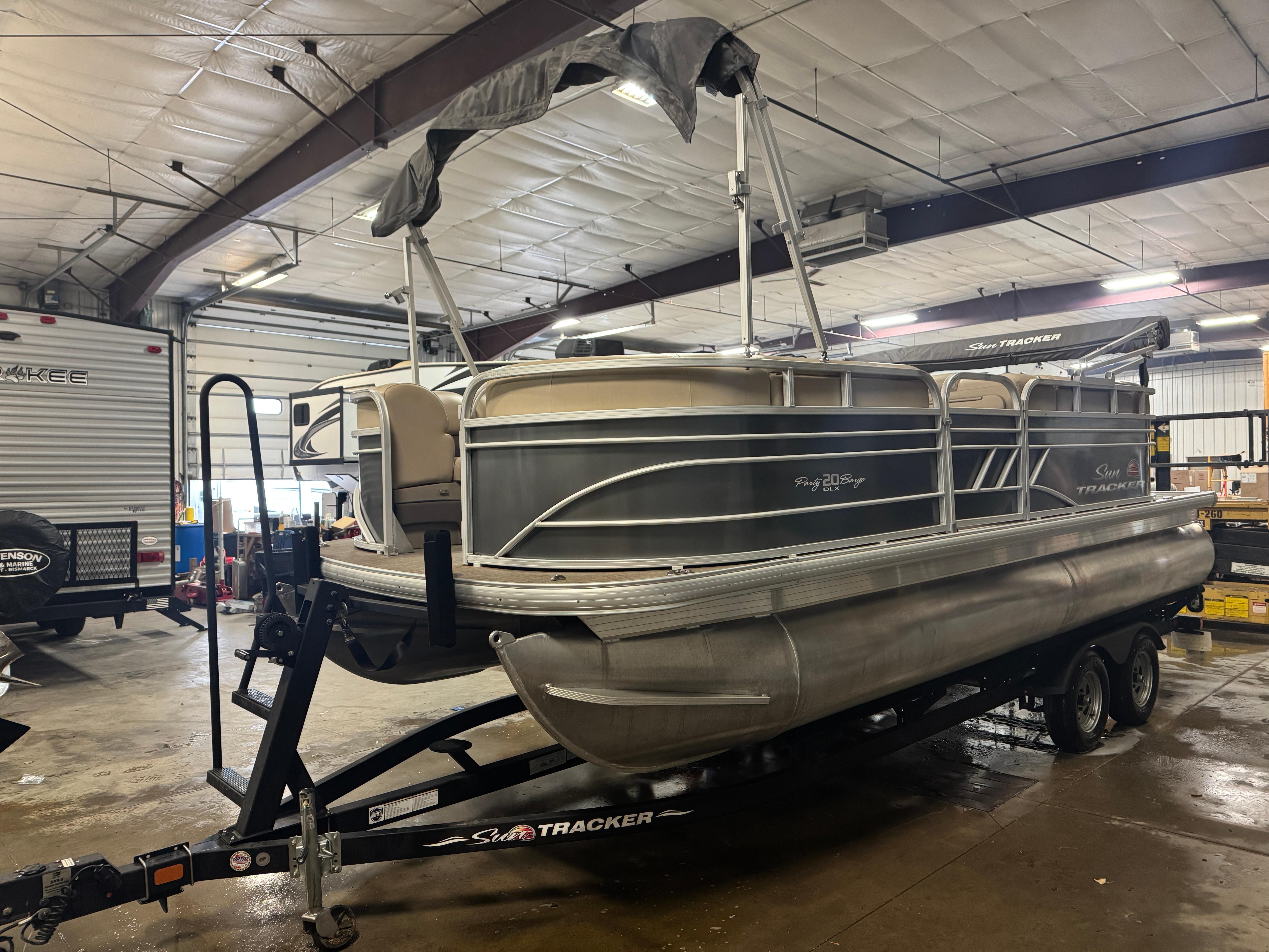 Sun Tracker Party Barge 20 DLX 2021 Sun Tracker Party Barge 20 DLX pontoon boat on trailer in indoor storage.