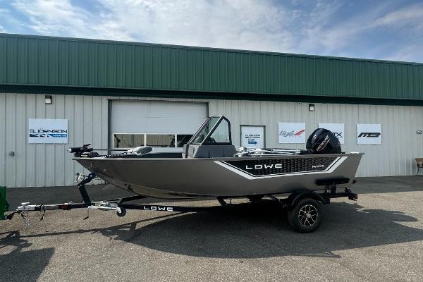 Lowe FM 1625 WT 2025 Lowe FM 1625 WT fishing boat on trailer, parked outside a warehouse.