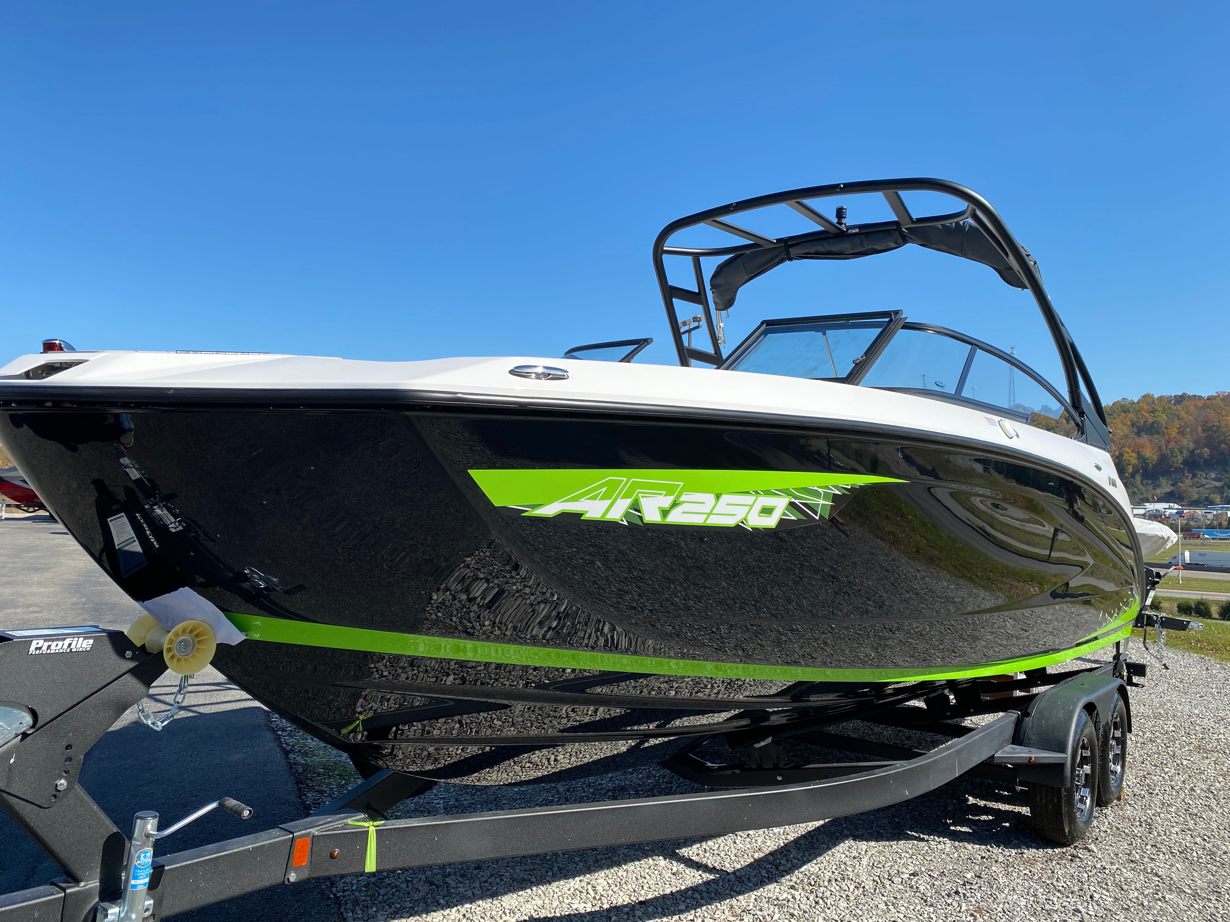 Yamaha Boats AR250 2021 Yamaha AR250 boat on trailer, black with green accents, under clear blue sky.