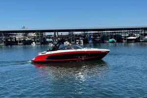 Cobalt R4 Surf 2023 Cobalt R4 Surf boat cruising on a sunny day near a marina.