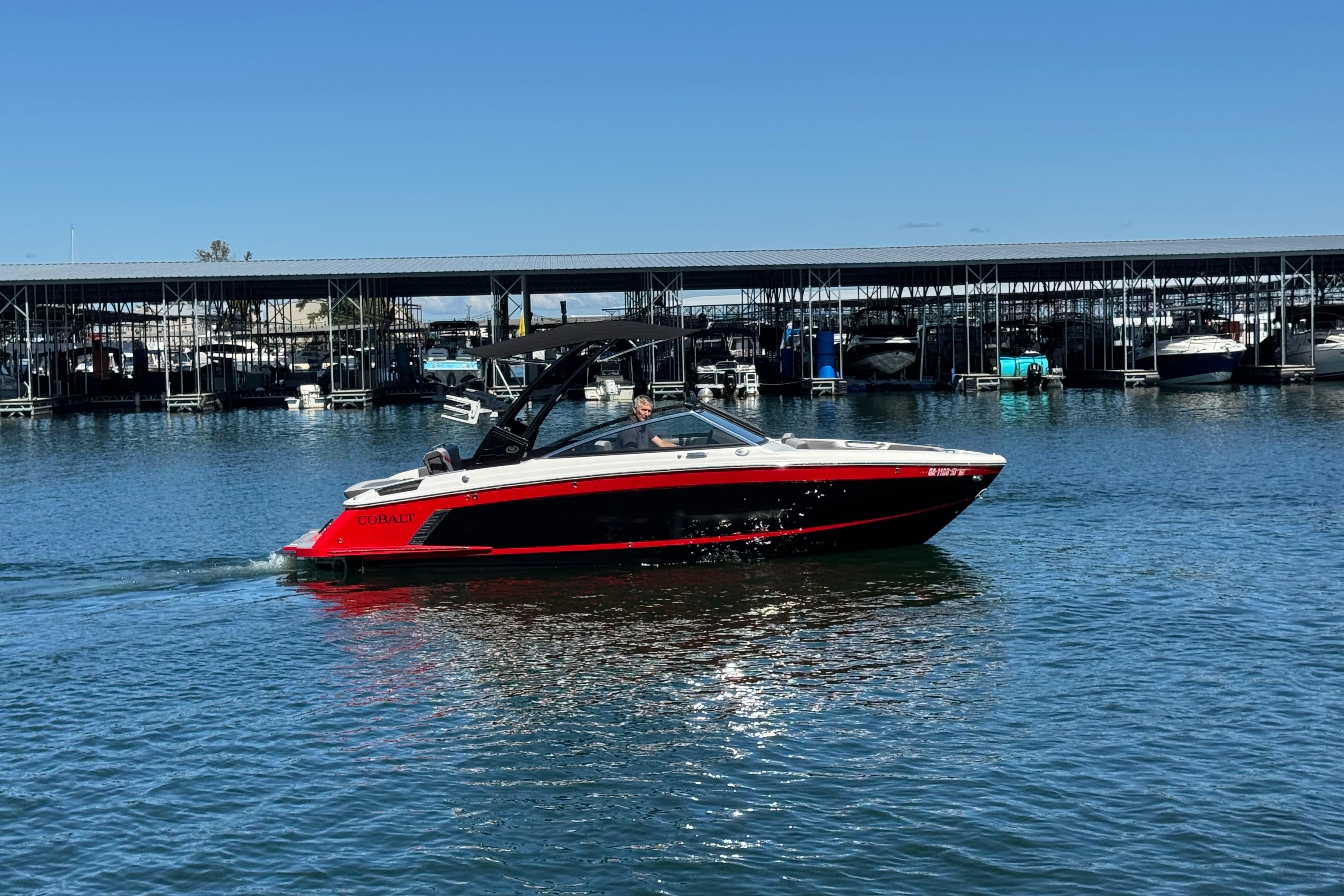 Cobalt R4 Surf 2023 Cobalt R4 Surf boat cruising on a sunny day near a marina.