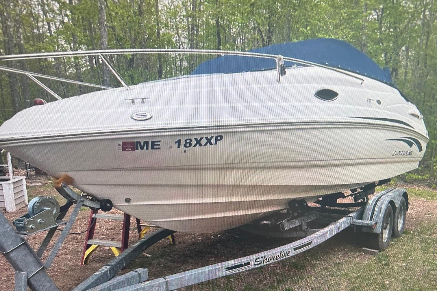 Chaparral 215SSi 2011 Chaparral 215SSi boat on trailer, parked in wooded area.