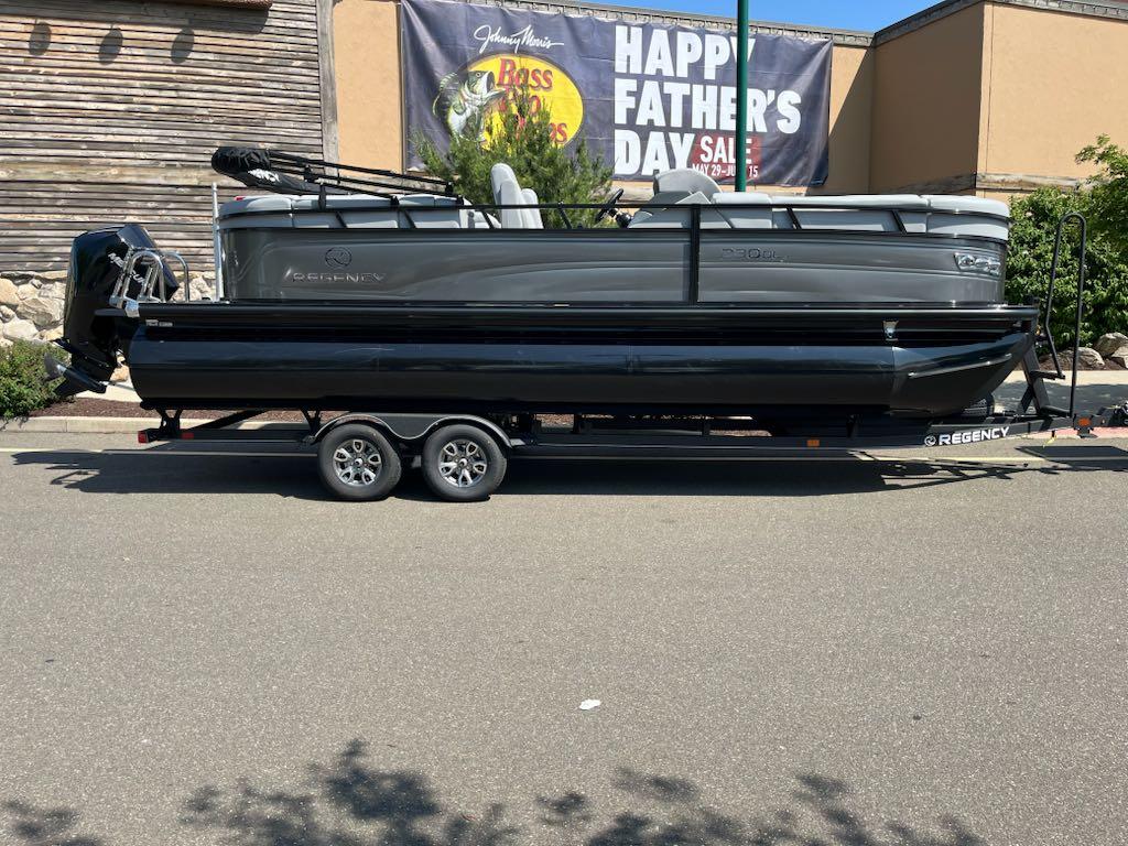 Regency 230 DL3 2025 Regency 230 DL3 pontoon boat on trailer, parked outdoors, Father's Day sale banner in background.
