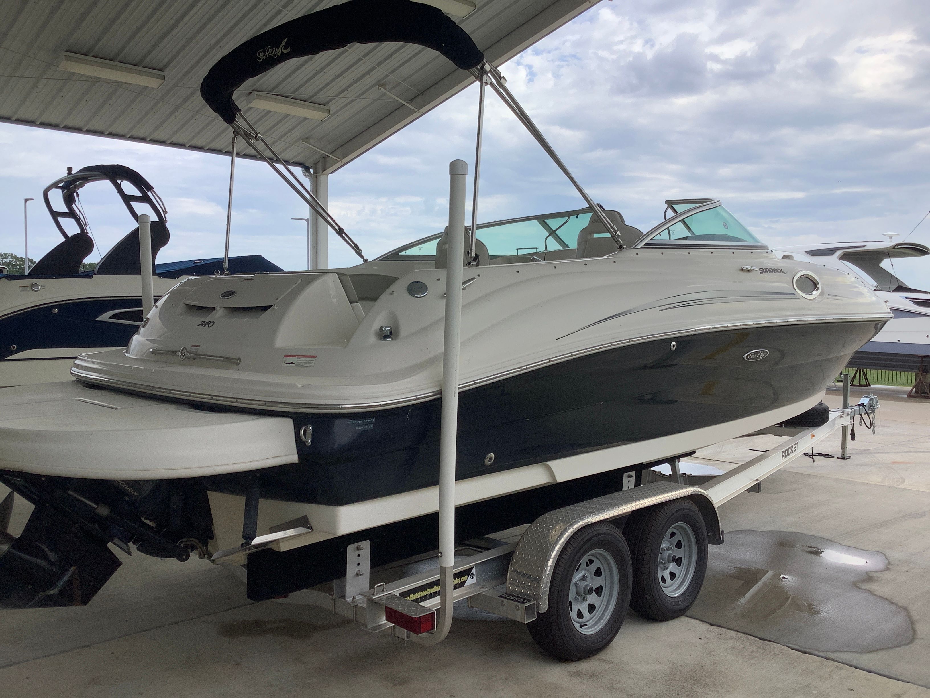 Sea Ray 240 Sundeck 2007 Sea Ray 240 Sundeck boat on trailer under shelter, side view.