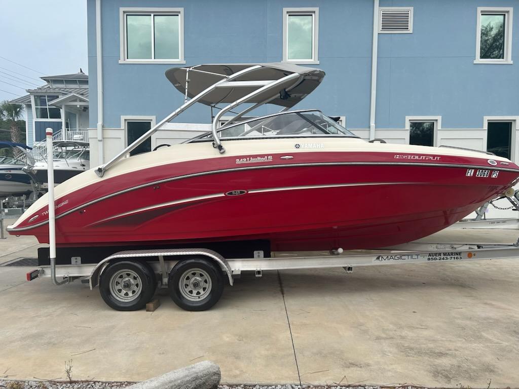 Yamaha Boats 242 Limited S 2014 Yamaha Boats 242 Limited S in red on a trailer, parked near a blue building.