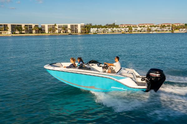 Bayliner M17 2024 Bayliner M17 boat cruising on clear blue water near a coastal city.