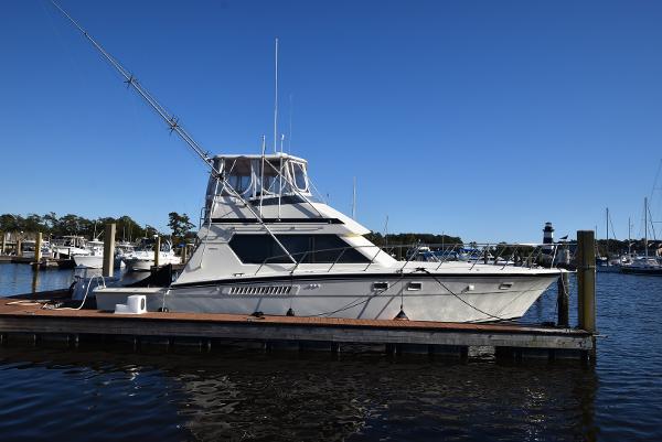 Hatteras 48 Convertible 1988 Hatteras 48 Convertible yacht docked at marina under clear blue sky.