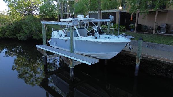 Blackfin 252 DC 2023 Blackfin 252 DC boat on lift by dock, surrounded by trees and calm water.