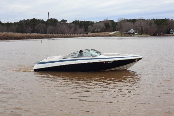 Cobalt 220 1996 Cobalt 220 boat cruising on a calm lake with wooded shoreline.