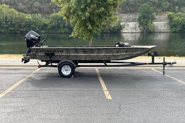 Tracker Grizzly 1654 T Sportsman 2026 Tracker Grizzly 1654 T Sportsman boat on trailer by a scenic river.