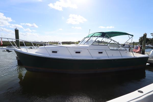 Mainship Pilot 34 2002 Mainship Pilot 34 boat docked, featuring a green canopy and sleek design.
