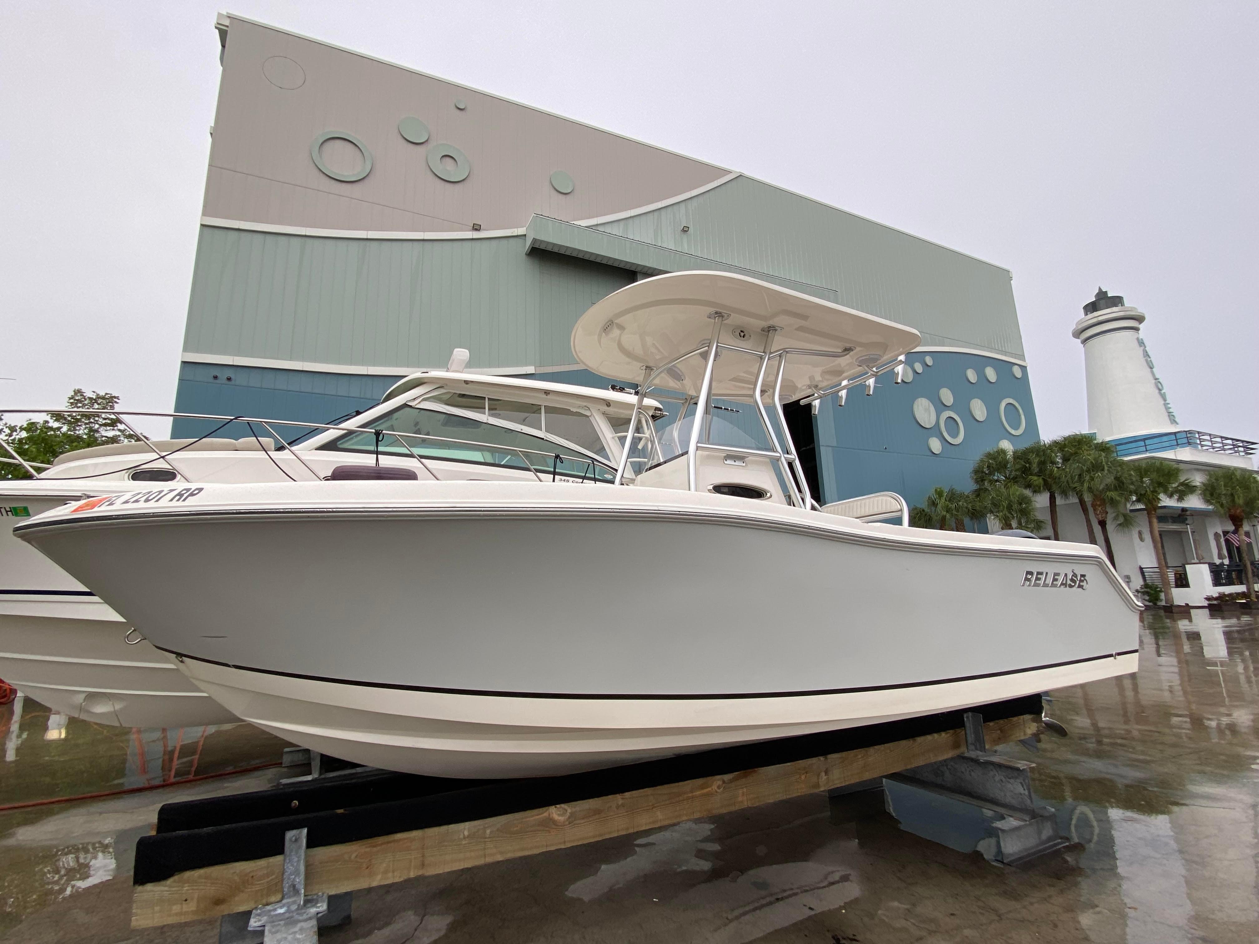Release 208 SXC 2018 Release 208 SXC boat displayed outdoors near a modern building and lighthouse.