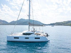 Lagoon 46 2022 Lagoon 46 catamaran sailing on clear blue waters with scenic mountain backdrop.