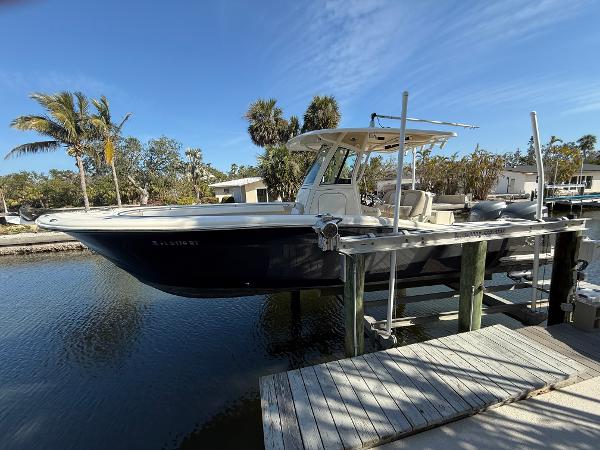 Scout 282 Sportfish 2009 Scout 282 Sportfish boat docked by a wooden pier, surrounded by palm trees.