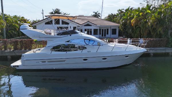 Azimut 42 Fly 2005 Azimut 42 Fly yacht docked by a waterfront house, surrounded by lush greenery.