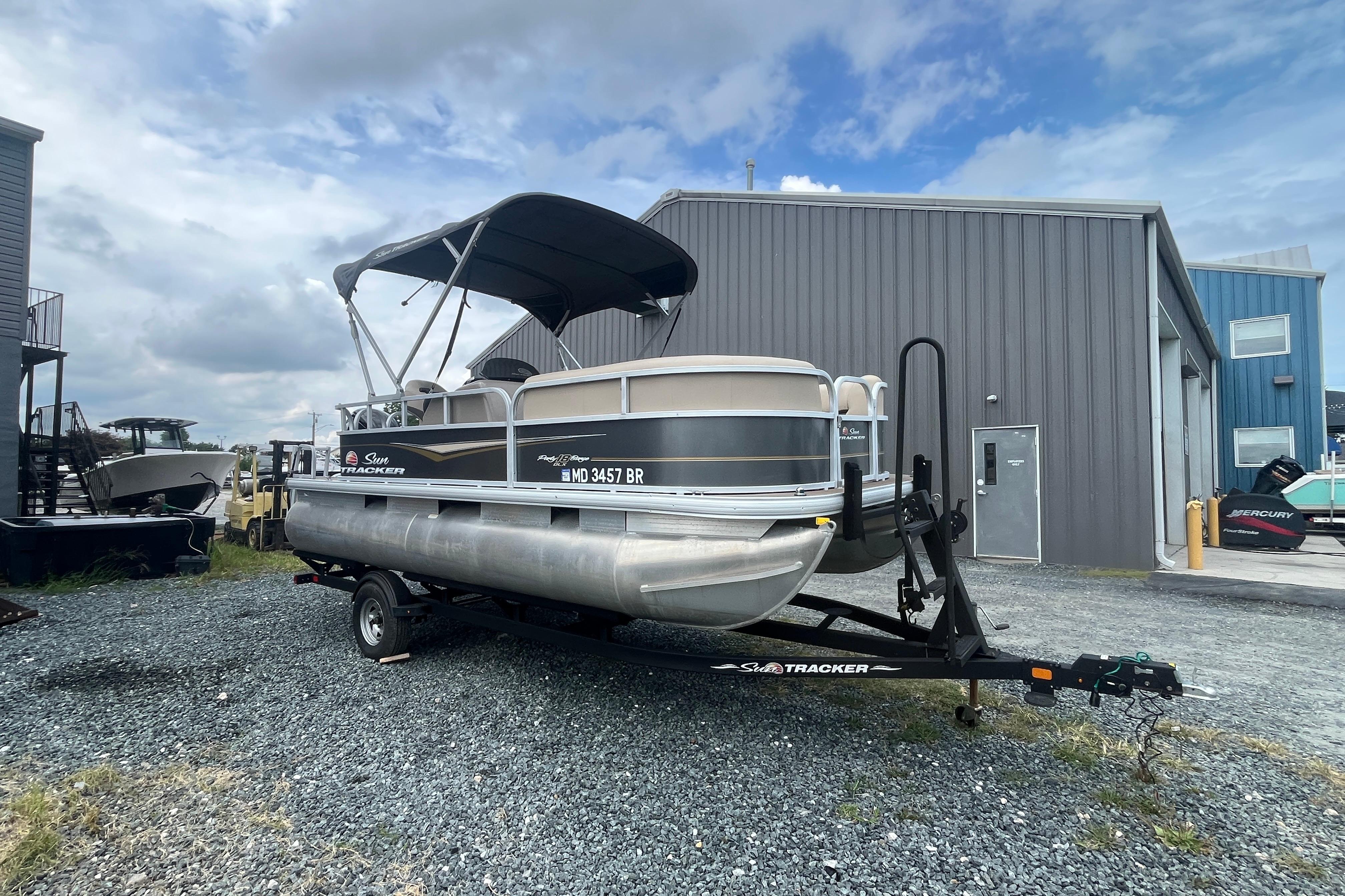 Sun Tracker Party Barge 18 DLX 2021 Sun Tracker Party Barge 18 DLX pontoon boat on trailer, parked outdoors.
