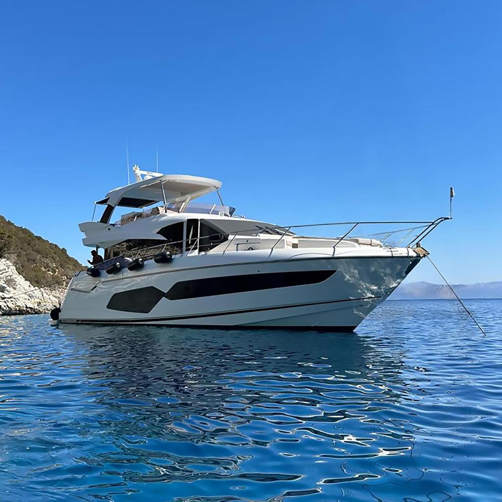 Sunseeker Manhattan 66 2019 Sunseeker Manhattan 66 yacht on clear blue water near rocky coastline.