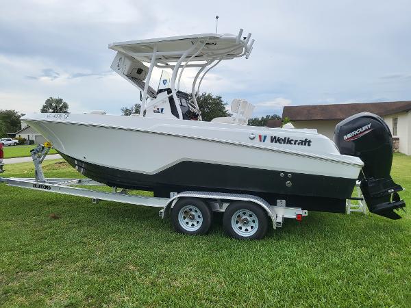 Wellcraft 222 Fisherman 2020 Wellcraft 222 Fisherman boat on trailer, parked on grass, with Mercury outboard motor.