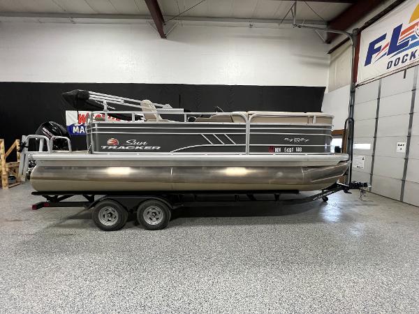 Sun Tracker Party Barge 20 DLX 2022 Sun Tracker Party Barge 20 DLX pontoon boat on a trailer in a showroom.