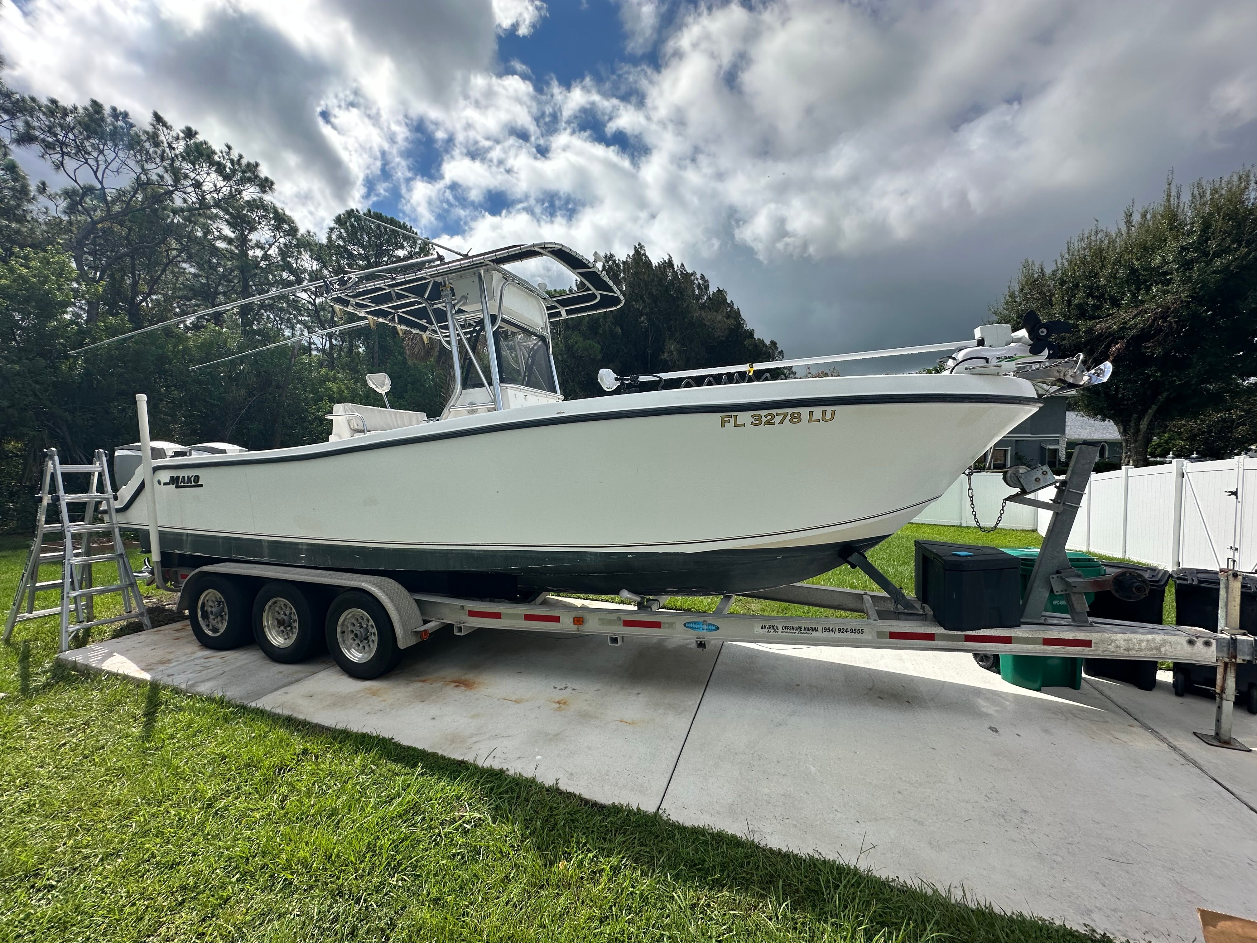 Mako 282 Center Console 2000 Mako 282 boat on trailer, parked outdoors under cloudy sky.
