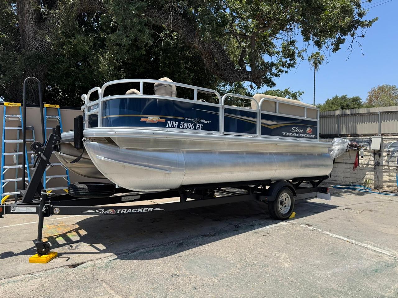 Sun Tracker Bass Buggy 16 XL Select 2023 Sun Tracker Bass Buggy 16 XL Select pontoon boat on trailer, parked outdoors.