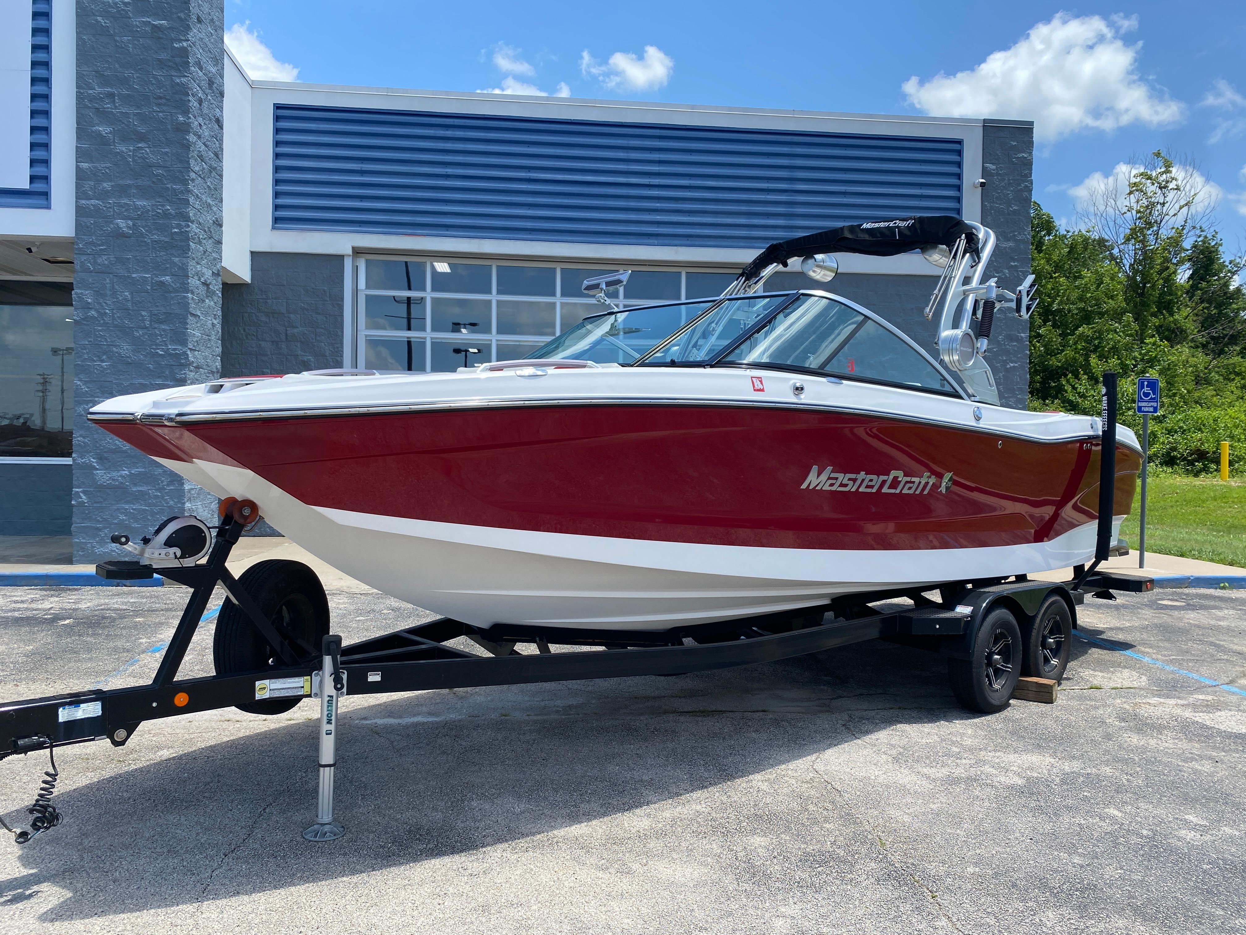 MasterCraft X26 2020 MasterCraft X26 boat in red and white on a trailer, parked outdoors.