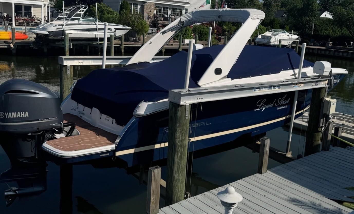 Regal 26 OBX 2019 Regal 26 OBX boat docked with Yamaha outboard motor, covered and elevated.