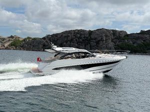Princess V50 Open 2024 Princess V50 Open yacht cruising on a scenic waterway with rocky backdrop.