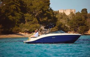 Sea Ray SPX210 2025 Sea Ray SPX210 boat cruising on clear blue water near a forested shoreline.