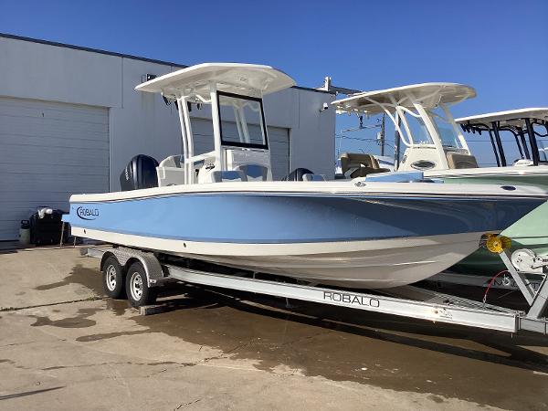 Robalo 246 Cayman 2023 Robalo 246 Cayman boat on a trailer, parked outdoors.