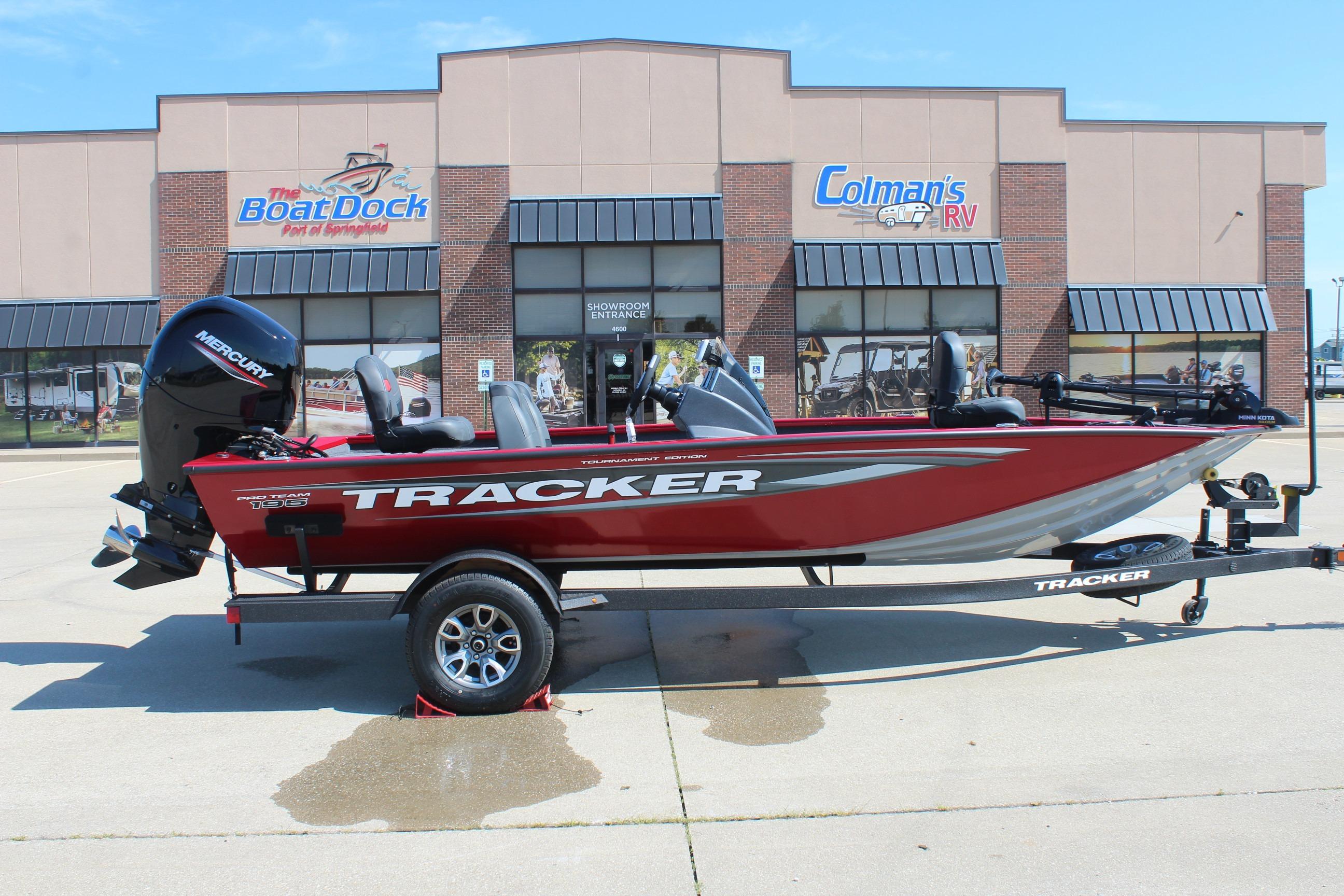 Tracker Pro Team 195 2026 Tracker Pro Team 195 boat in red, parked outside dealership, with Mercury engine.