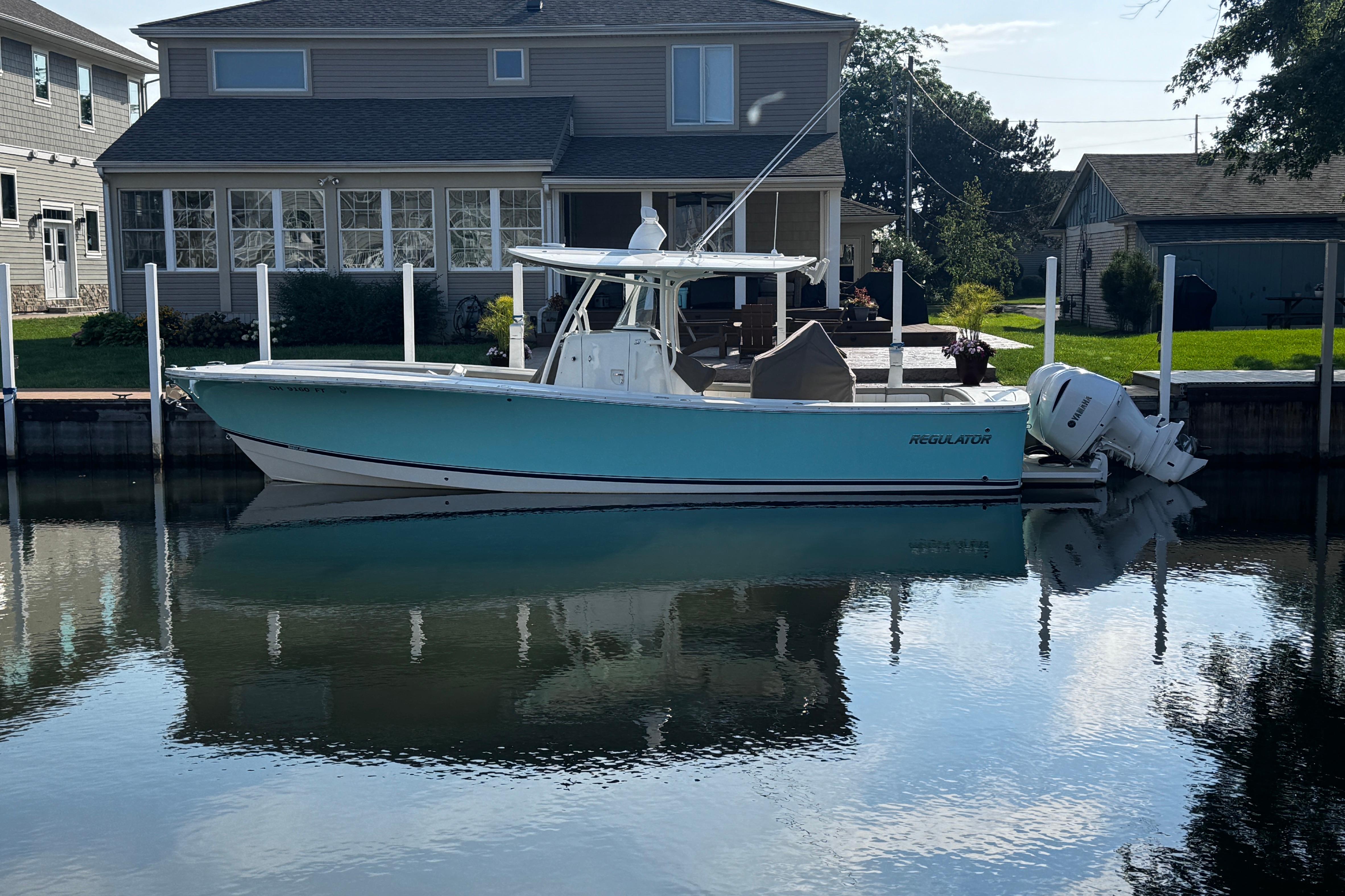 Regulator 31 2018 Regulator 31 boat docked by a waterfront house, reflecting on calm water.