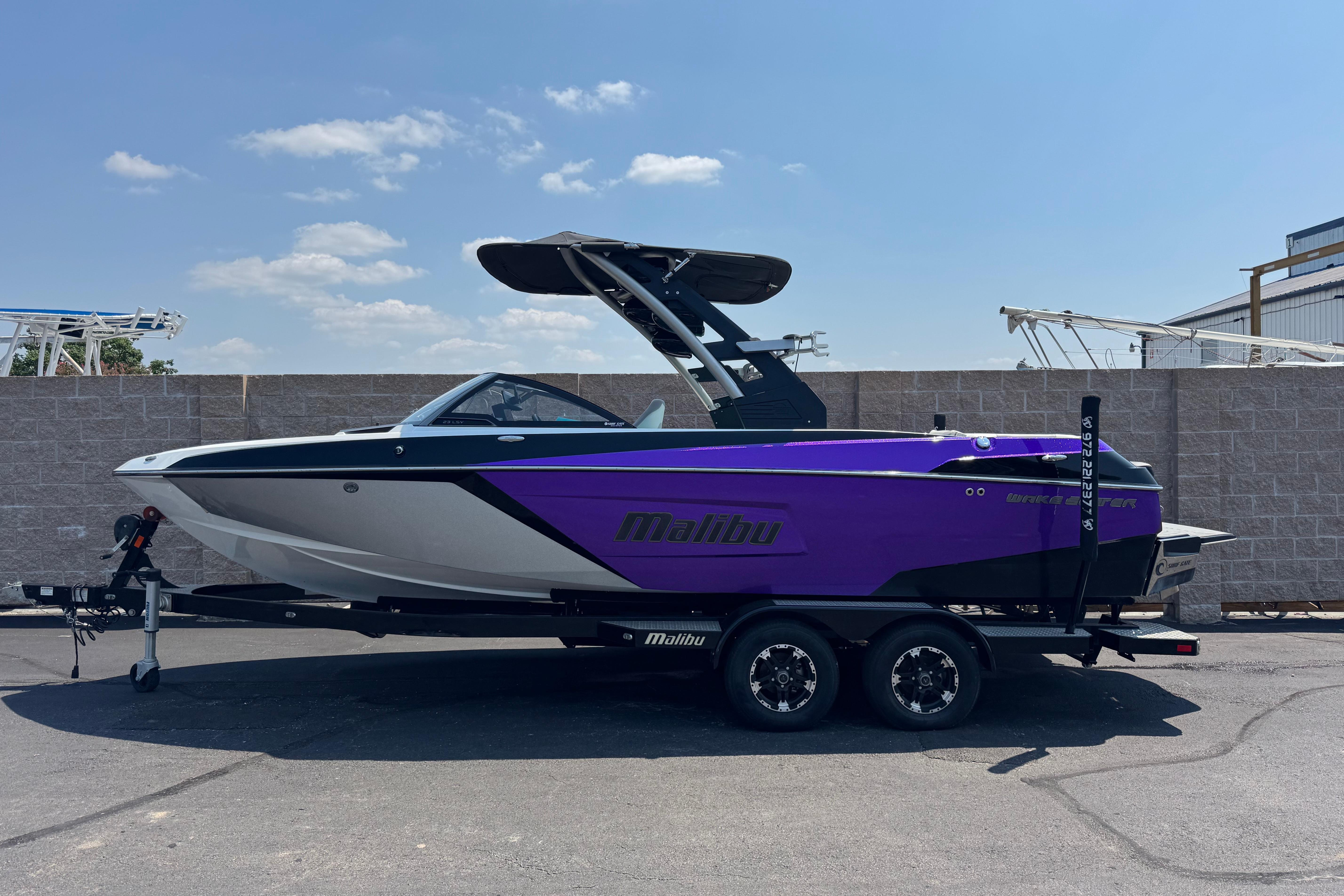 Malibu Wakesetter 23 LSV 2018 Malibu Wakesetter 23 LSV boat on trailer, purple and white design, parked outdoors.