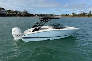 Regal LX6 2026 Regal LX6 boat on calm water with scenic coastal background.