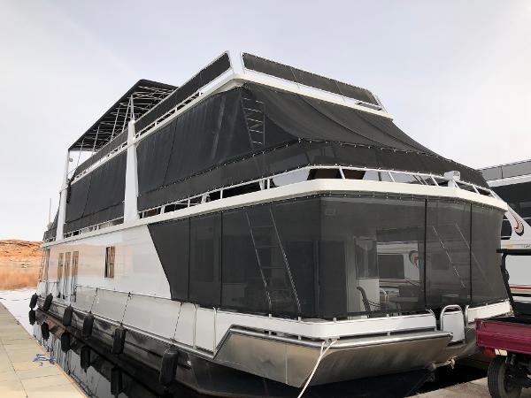 Custom Endless Summer Custom 2001 Endless Summer houseboat with black mesh coverings docked at marina.