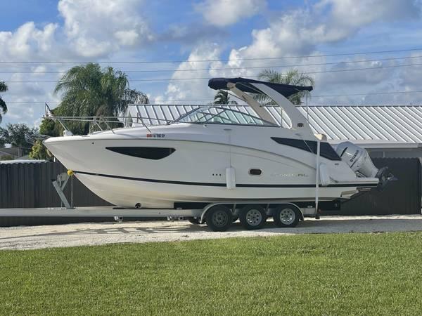Regal 26 XO 2020 Regal 26 XO boat on trailer, parked outdoors under a cloudy sky.