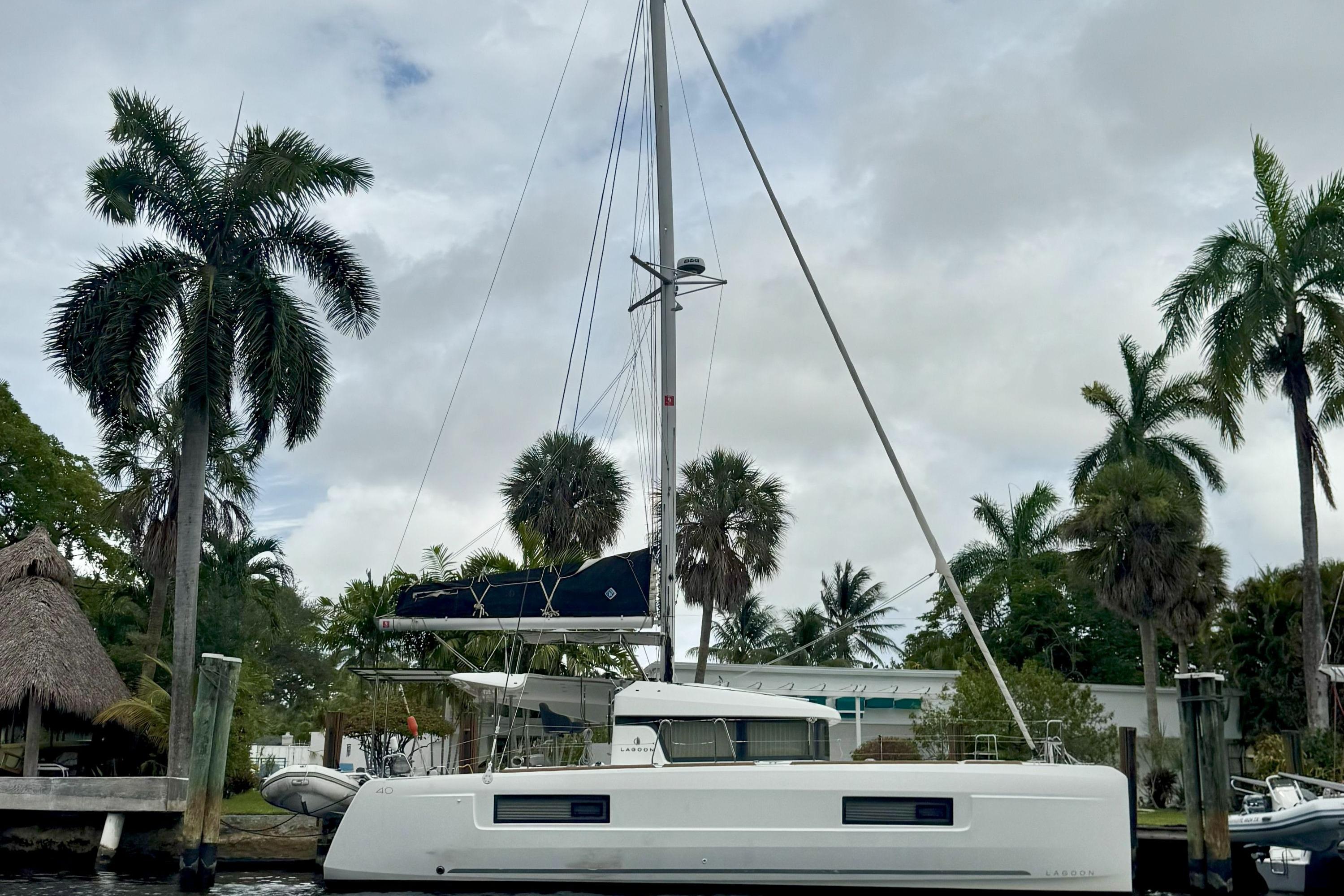 Lagoon 40 2022 Lagoon 40 catamaran docked near palm trees under cloudy sky.