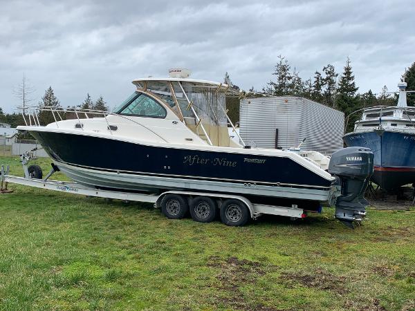 Pursuit Offshore 335 2007 Pursuit OS 335 boat on trailer, parked on grass, with Yamaha outboard motor.