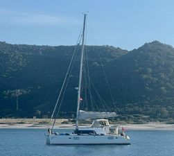 Lagoon 440 2010 Lagoon 440 catamaran anchored in serene coastal waters with mountainous backdrop.