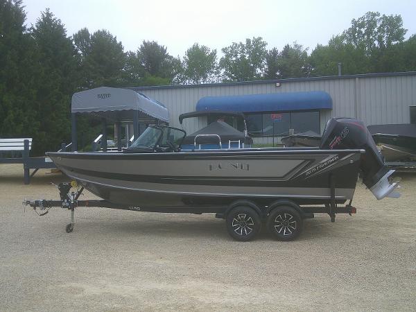 Lund 2075 Fisherman 2025 Lund 2075 Fisherman boat on trailer, parked outdoors near a building.