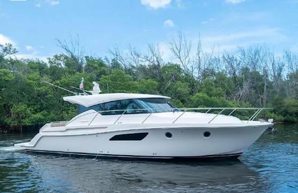 Tiara Yachts C44 Coupe 2015 Tiara Yachts C44 Coupe cruising on a serene waterway with lush greenery.