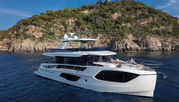 Absolute Navetta 64 2025 Absolute Navetta 64 yacht cruising near a rocky coastline.