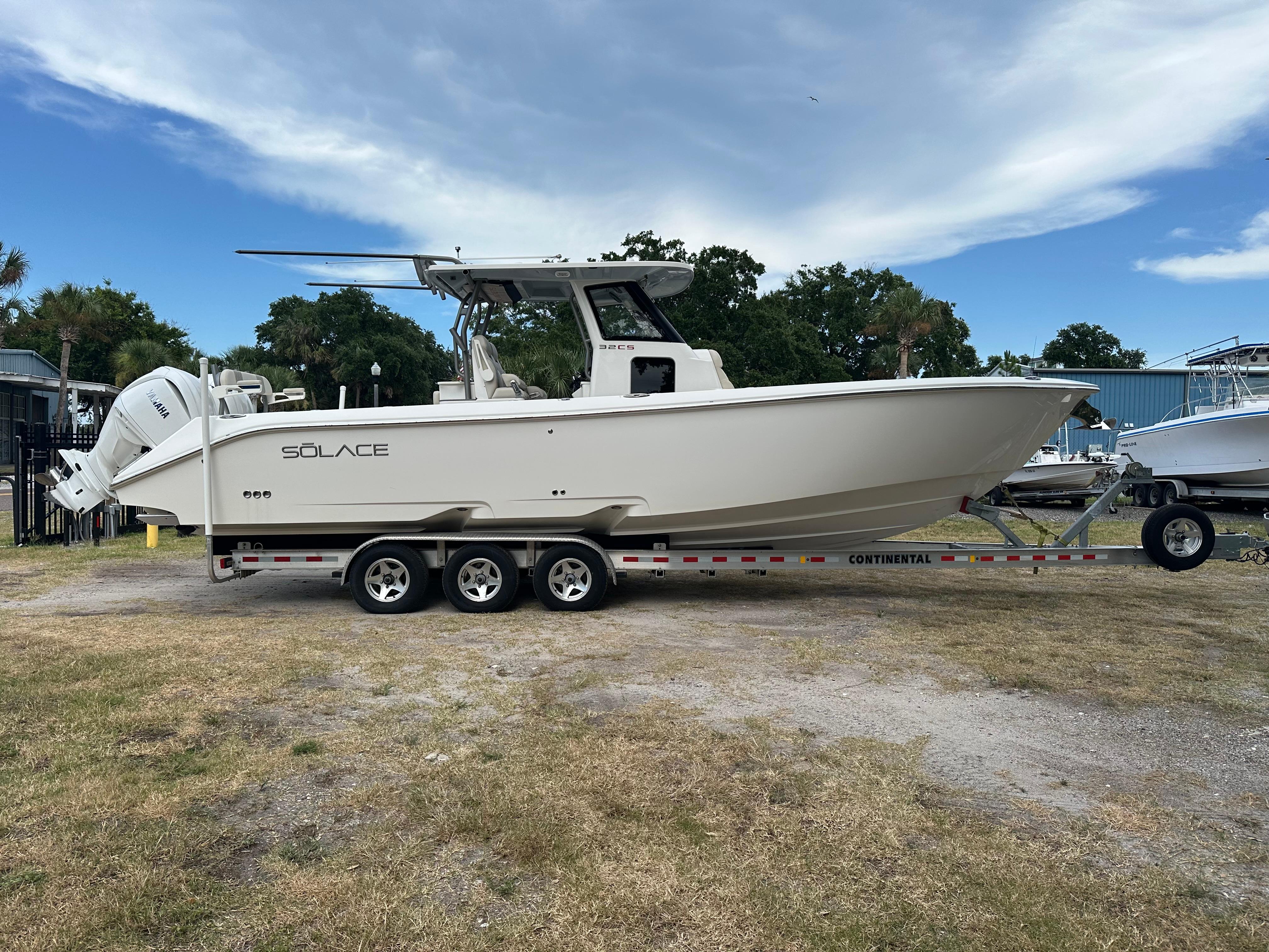 Solace 32 CS 2024 Solace 32 CS boat on trailer, parked outdoors under a partly cloudy sky.