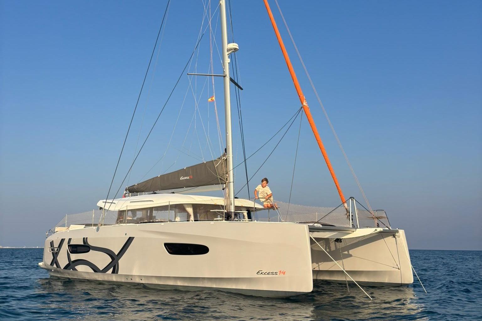 Excess 14 2025 Excess 14 catamaran sailing on calm sea under clear blue sky.