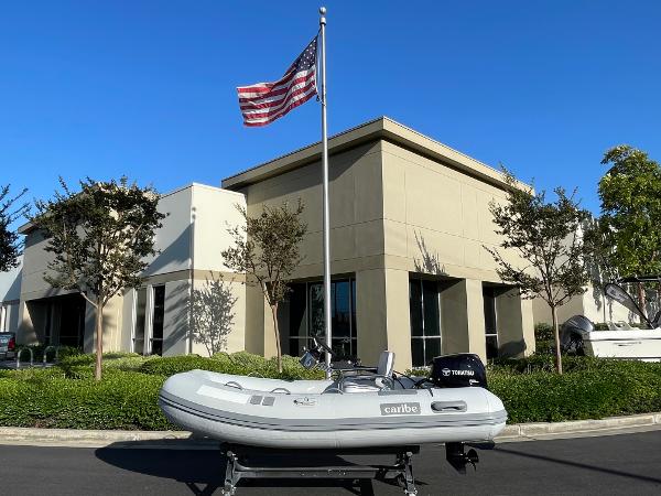 Caribe C10X 2013 Caribe C10X inflatable boat with Yamaha motor, parked near modern building and flagpole.